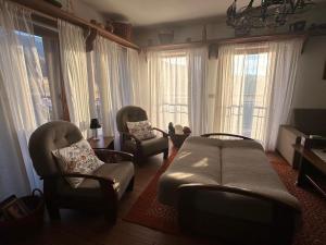 a living room with a couch and chairs and windows at Chata pri lese,Liptov in Bobrovec