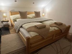 a bedroom with a large wooden bed with blankets and pillows at Chata pri lese,Liptov in Bobrovec