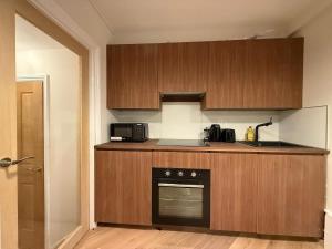 a kitchen with wooden cabinets and a black oven at Fantastic Two Bed Flat In Paddington Central London Zone 1 in London