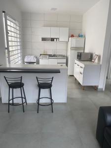 una cucina con 2 sgabelli da bar e piano di lavoro di Casa da Praia Edmara a Guaratuba Altre 8 foto