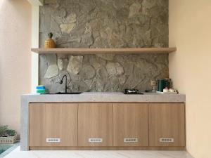 a kitchen with a sink and a stone wall at Kamaya Villa Jogja in Ngaglik