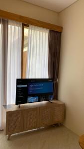 a flat screen tv sitting on a stand in front of a window at Kamaya Villa Jogja in Ngaglik