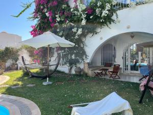 an umbrella in the yard of a house with flowers at South Hammamet Pool Villa in Hammamet Sud