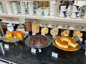 a counter with different types of cakes and other desserts at Six's Hotel in Jacareí +7 photos