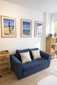 a blue couch in a living room with pictures on the wall at Appartement deux pièces élégant avec Vue sur Parc - Plage & Centre-Ville à Pied in Cabourg