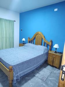 een slaapkamer met een bed en een blauwe muur bij Departamentos Los corrales in San Andrés de Giles