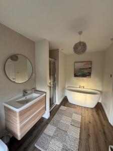 a bathroom with a tub and a sink and a mirror at Pear Tree Cottage, Portstewart in Portstewart +21 photos