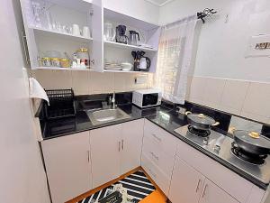 a small kitchen with white cabinets and a sink at Luxury small Homely Apt villa in Kisumu