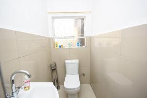 een badkamer met toilet, wastafel en raam bij Airport Lodge Hotel in Kempton Park