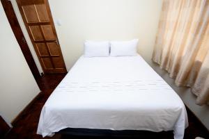 een wit bed in een kamer met een raam bij Airport Lodge Hotel in Kempton Park