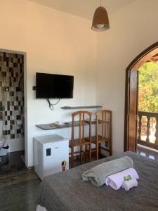 a bedroom with a bed and a tv on the wall at Pousada Flat Royal Suíte com varanda e rede in Itapecerica +23 photos