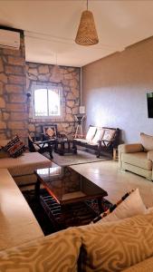 een woonkamer met banken en een stenen muur bij Ferme d'hôtes Safi in Safi