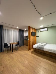 een slaapkamer met een bed, een tafel en een tv bij Pine Aparthotel in Shekhvetili