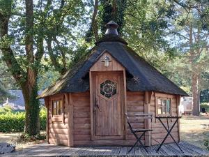 een kleine blokhut met een zwart dak bij camping de brocéliande in Néant-sur-Yvel
