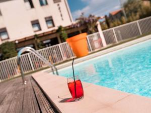 a drink sitting on a table next to a swimming pool at ibis Styles Carcassonne La Cité in Carcassonne