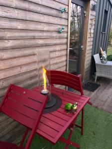 eine rote Bank mit einer Kerze auf einem Tisch in der Unterkunft Tiny House indépendante tout confort full équipement adult only-seulement in Morhange