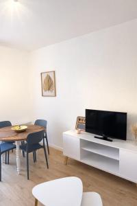 a living room with a television and a dining room table at Appartement deux pièces élégant avec Vue sur Parc - Plage & Centre-Ville à Pied in Cabourg
