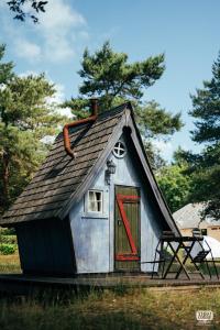 een klein huis met een rode deur in een tuin bij camping de brocéliande in Néant-sur-Yvel