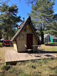 een klein huis met een tafel en stoelen op een terras bij camping de brocéliande in Néant-sur-Yvel