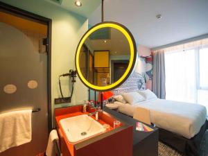 een slaapkamer met een bed, een wastafel en een spiegel bij ibis Styles Tbilisi Center in Tbilisi City