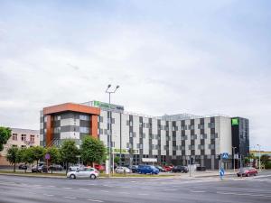 un grande edificio con auto parcheggiate in un parcheggio di ibis styles Grudziadz a Grudziądz