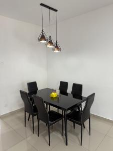 a black dining room table with black chairs and a light at De Little Cabin - 7mins to Sunway Iost World of Tambun in Ipoh