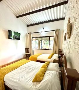 una camera con tre letti con cuscini gialli di Finca Hotel Buenos Aires a Guamal