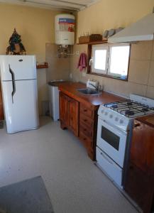 eine Küche mit einem weißen Herd und einem Kühlschrank in der Unterkunft Chacra La Elena - Casa container a 15km de Madryn in Puerto Madryn