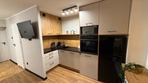 a kitchen with white cabinets and black appliances at W Centrum in Piła +20 photos