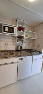 een keuken met witte kasten en een magnetron bij El encanto del lago in Bariloche