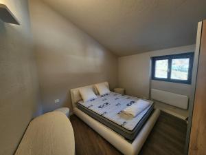 a small room with a bed with a window at Valmalenco Home in Chiesa in Valmalenco