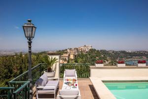 a balcony with chairs and a pool and a street light at Hotel Castel Vecchio in Castel Gandolfo