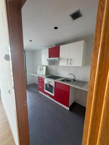 een keuken met rode en witte kasten en een wastafel bij Apartament H&C in Madrid
