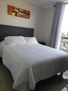 a bedroom with a bed with white sheets and a window at Zapahuira in Arica