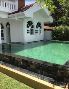 a pool in the backyard of a house with green water at Theodore Hotel - Negombo in Negombo
