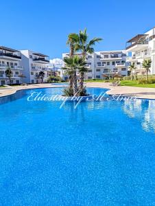 een groot zwembad met palmbomen voor een gebouw bij EliteStay by Al Amir in Cabo Negro