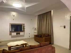 a living room with two couches and a flat screen tv at Flamingo 1 spacious solar powered 2 bedroom home with a stocked ready kitchen in Jos