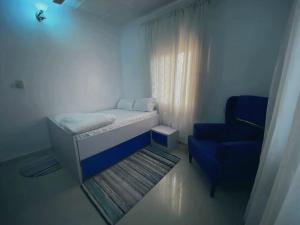 a small room with a bed and a blue chair at Flamingo 1 spacious solar powered 2 bedroom home with a stocked ready kitchen in Jos