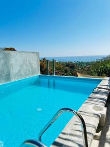 a blue swimming pool with a view of the ocean at Hotel Quinto Sol in Mazunte