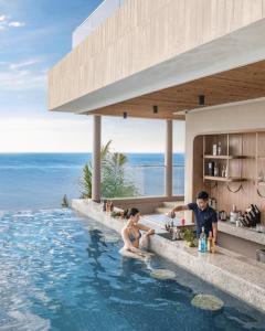 ein Mann und eine Frau sitzen in einem Swimmingpool in der Unterkunft The Moonlight Apartment- Mandala Mui Ne in Ấp Thiẹn Ái