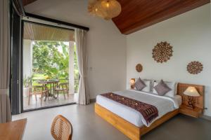 a bedroom with a bed and a patio with a table at Waringin Villa Ubud in Ubud