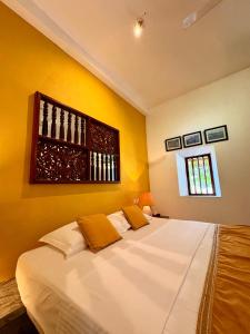 een slaapkamer met een groot wit bed met gele muren bij Villa Kubura in Hikkaduwa