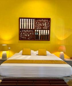 een slaapkamer met een groot bed met gele muren bij Villa Kubura in Hikkaduwa