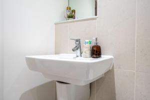 a white sink in a bathroom with a mirror at Stylish 2 Bedroom APT with Balcony in Leeds +23 photos
