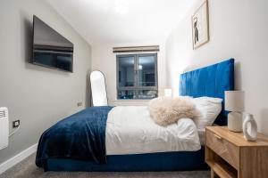 a bedroom with a blue bed and a window at Stylish 2 Bedroom APT with Balcony in Leeds
