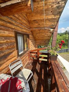 una veranda di una baita di tronchi con panchina e finestra di Căsuța Bunicilor de la Munte a Ceahlău
