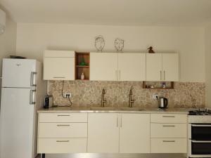 a kitchen with white cabinets and a white refrigerator at The corner in Sde Ilan in Sede Ilan