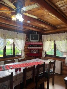 a dining room with a table and chairs and a tv at Căsuța Bunicilor de la Munte in Ceahlău +42 photos