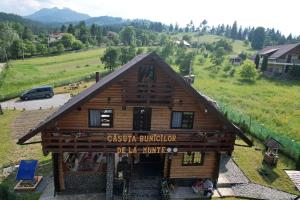 un edificio con un cartello sopra la baita di tronchi di Căsuța Bunicilor de la Munte a Ceahlău