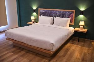 een slaapkamer met een groot wit bed met twee lampen bij Hotel Demanchi By The Leaf in Kārandūkai